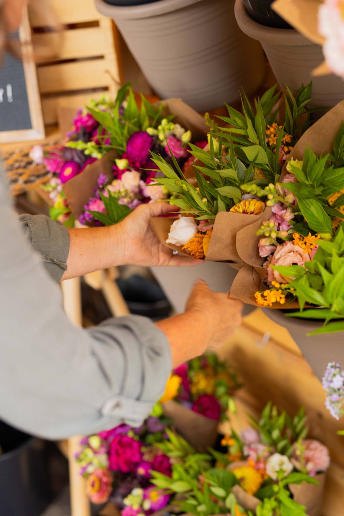 AG Flower Seeds | Person arranging flowers in brown paper bags with a blurred background